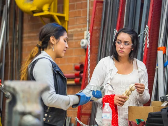 Two female students in the workshop, discussing and working.