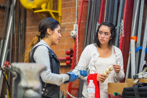 Two female students in the workshop, discussing and working.